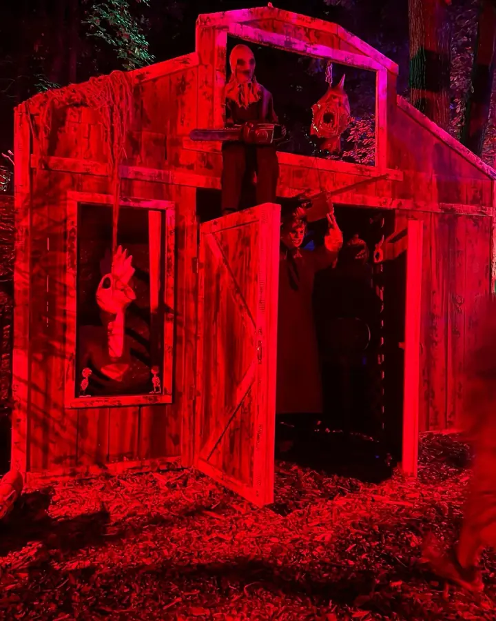A barn facade lit deep red with figures in the windows.