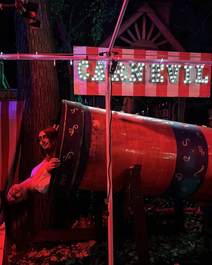 The CARNEVIL sideshow: a lit marquee, a striped circus cannon and an actor leaning out of it.