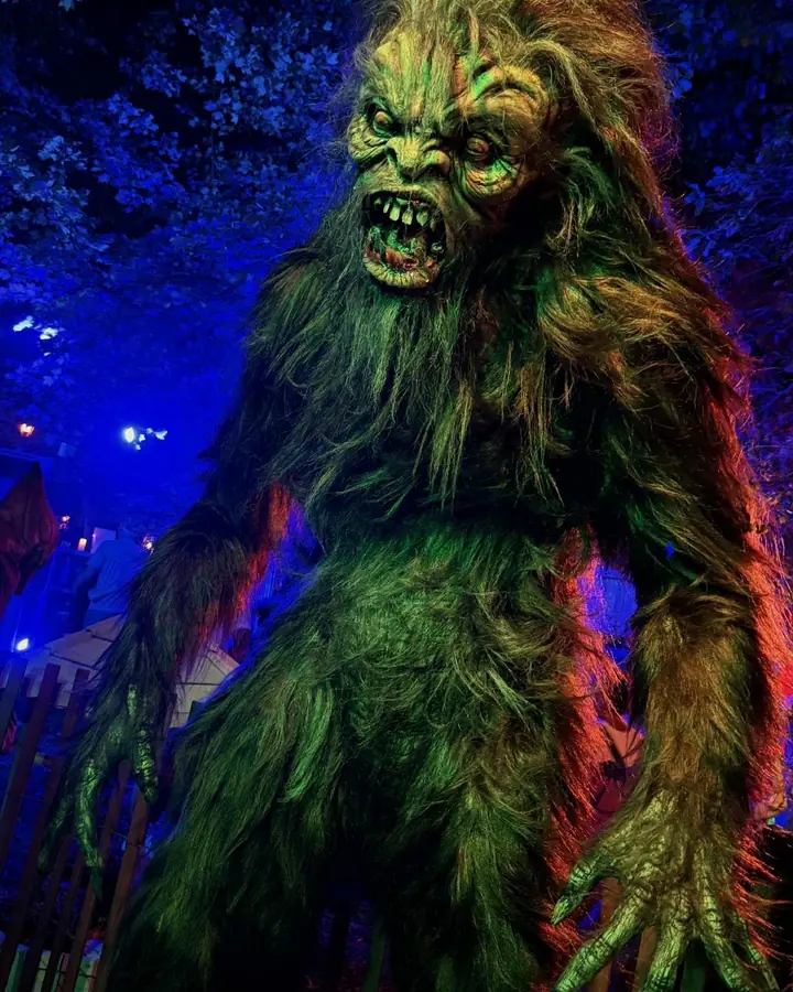 A hulking hairy creature lit green and blue among the trees.
