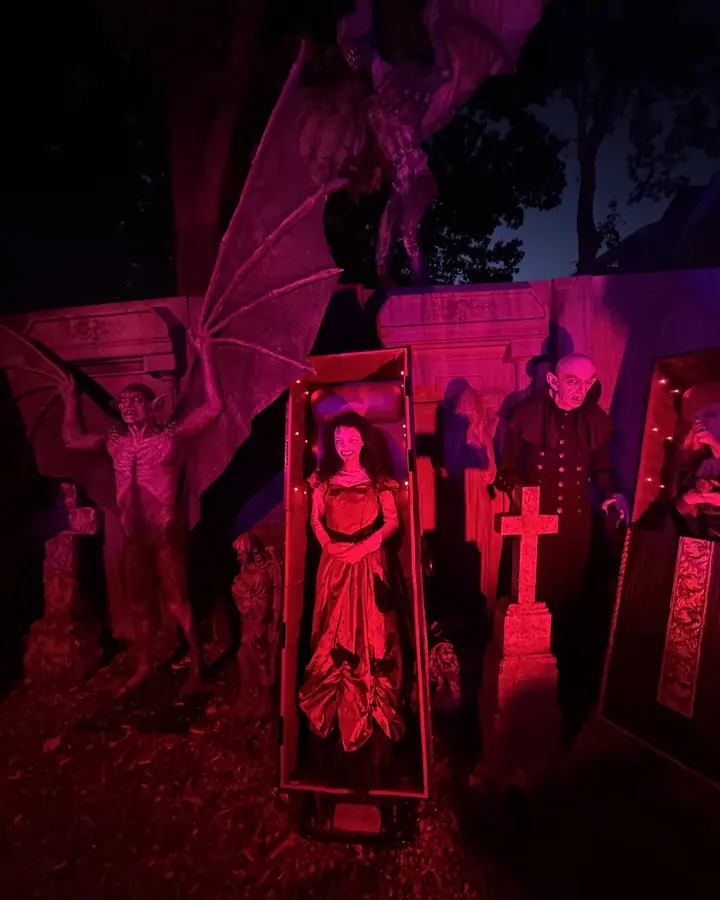 A vampire crypt lit red, with an open coffin and a winged gargoyle above it.