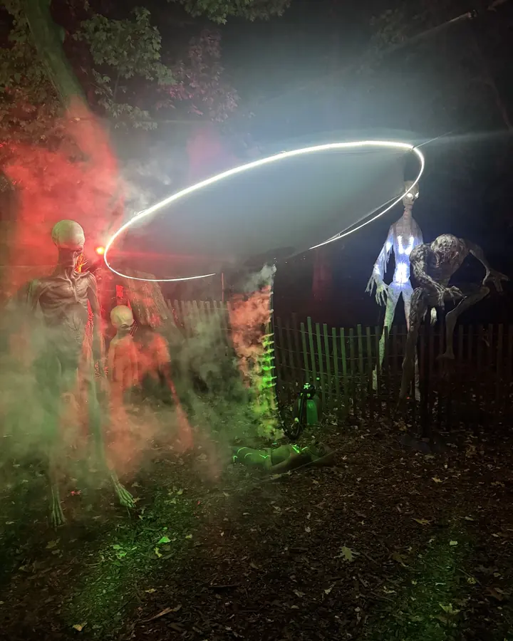 A glowing ring of light hovering over skeletal aliens in fog.